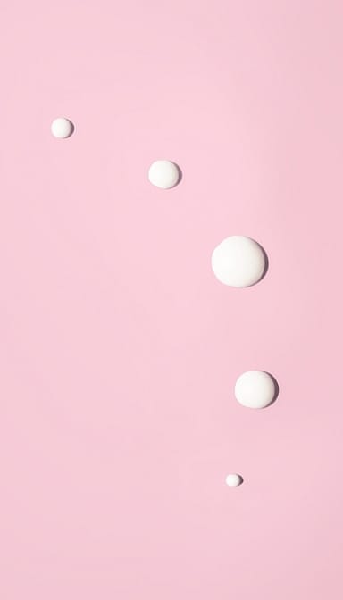 Smoothing Eye Cream Wild Rose & White Tea droplets on a pink background.