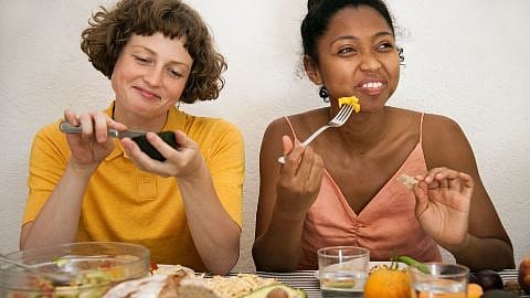 Two women sitting next to eachother and eating.