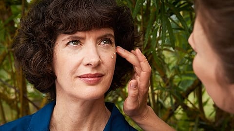 Woman applying eye cream to another woman.