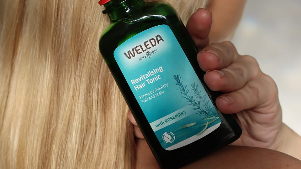 woman holding hair tonic in hand with hair