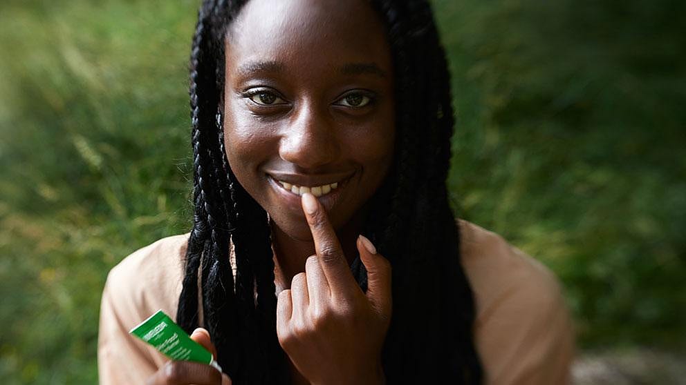 Dark skin girl applying Skin Food Lip Balm.